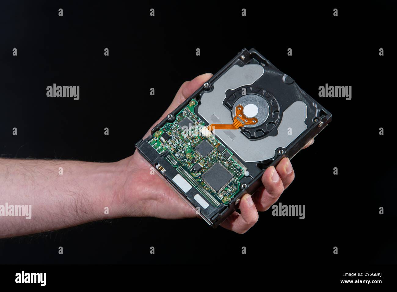 Gros plan de la main de l'homme tenant un disque dur d'ordinateur sur fond noir Banque D'Images