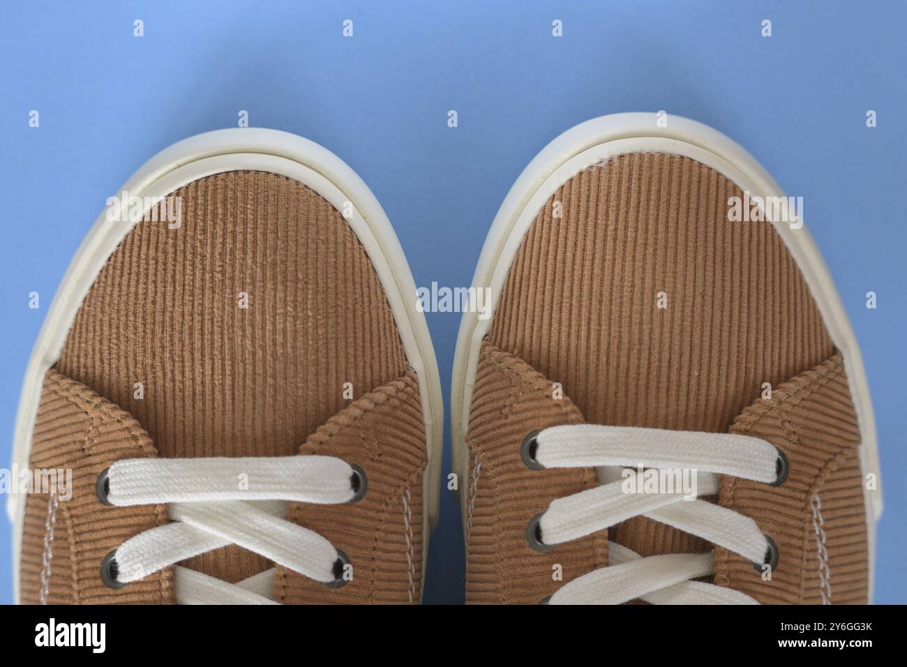 Gros plan des chaussures de basket en velours côtelé beige sur fond bleu Banque D'Images