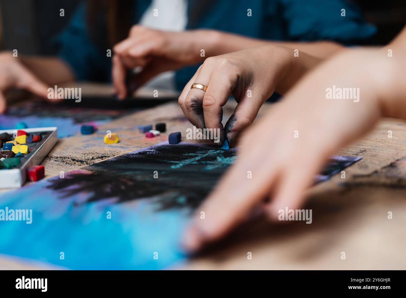 Artistes engagés créant des dessins pastel vibrants dans un atelier créatif Banque D'Images