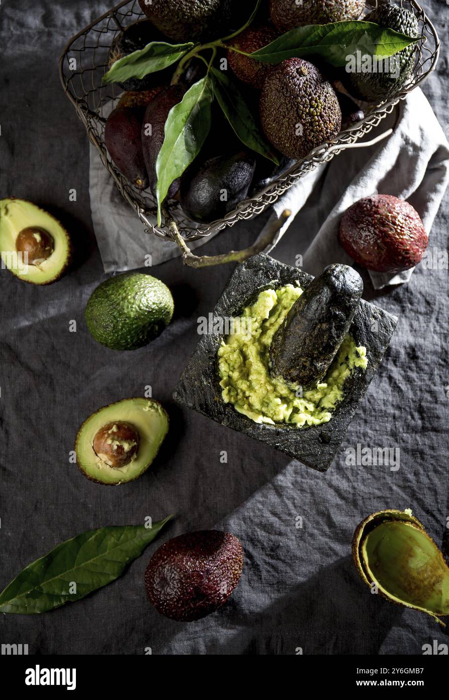 Nourriture, avocat. Guacamole. Sauce guacamole mexicaine dans mortier de pierre, panier plein avec avocat, moitié d'avocat sur nappe de lin. Vue de dessus. Copier l'espace Banque D'Images