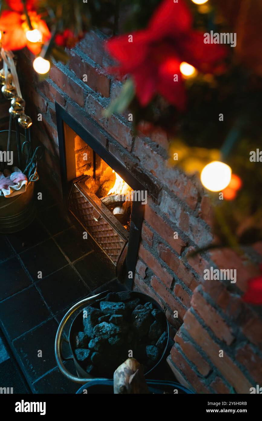 Cheminée festive chaleureuse et confortable dans le salon avec charbon, bûches de feu et lumières fériées de Noël le matin de Noël 01 Banque D'Images