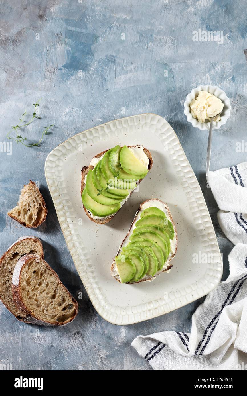Vue de dessus pain Sourdough sandwich ouvert avec avocat tranché, fromage à la crème et miel Banque D'Images