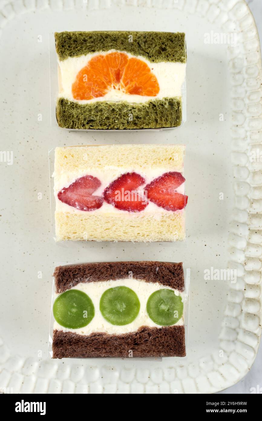 Vue de dessus divers sandwichs aux fruits japonais, chocolat, pain ordinaire et thé vert avec crème fouettée et fruits tranchés Banque D'Images