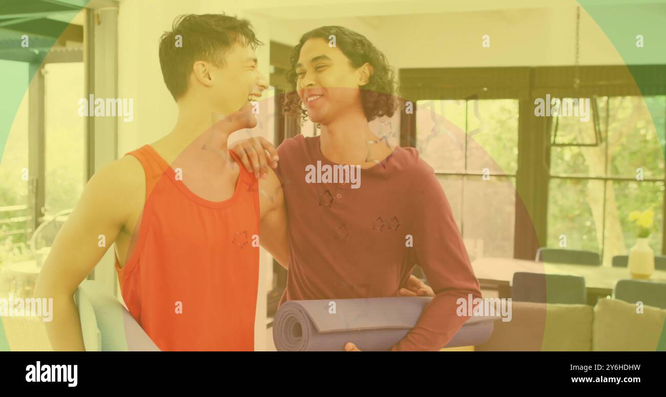 Image d'anneaux arc-en-ciel, de cœur et d'étoiles sur un couple masculin gay heureux et diversifié embrassant à la maison Banque D'Images