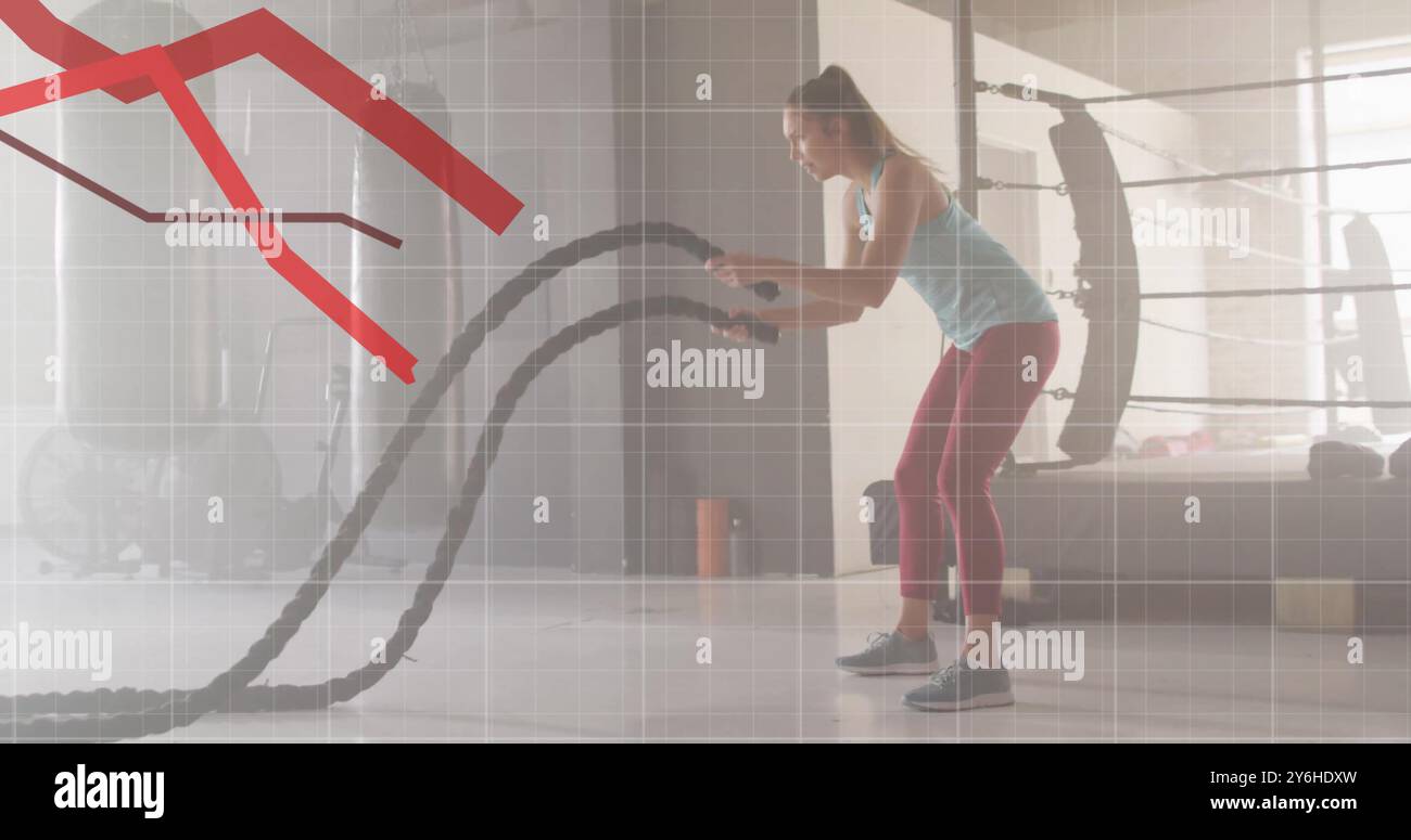 En utilisant des cordes de combat, femme exerçant sur l'image de graphique rouge déclinante Banque D'Images