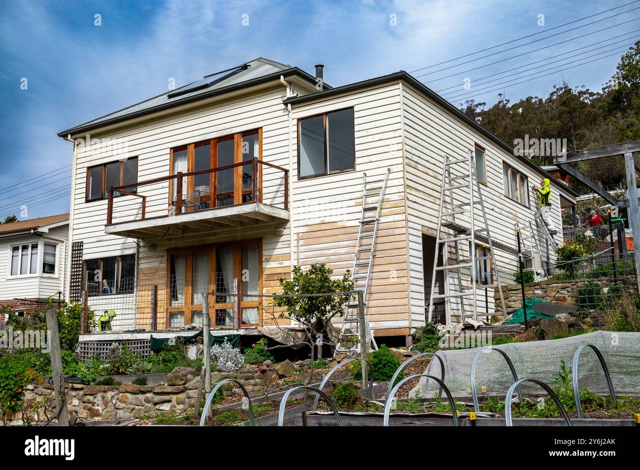 Peintres préparant une vieille maison en bois de banlieue de deux étages à Hobart pour repeindre et rénover Banque D'Images