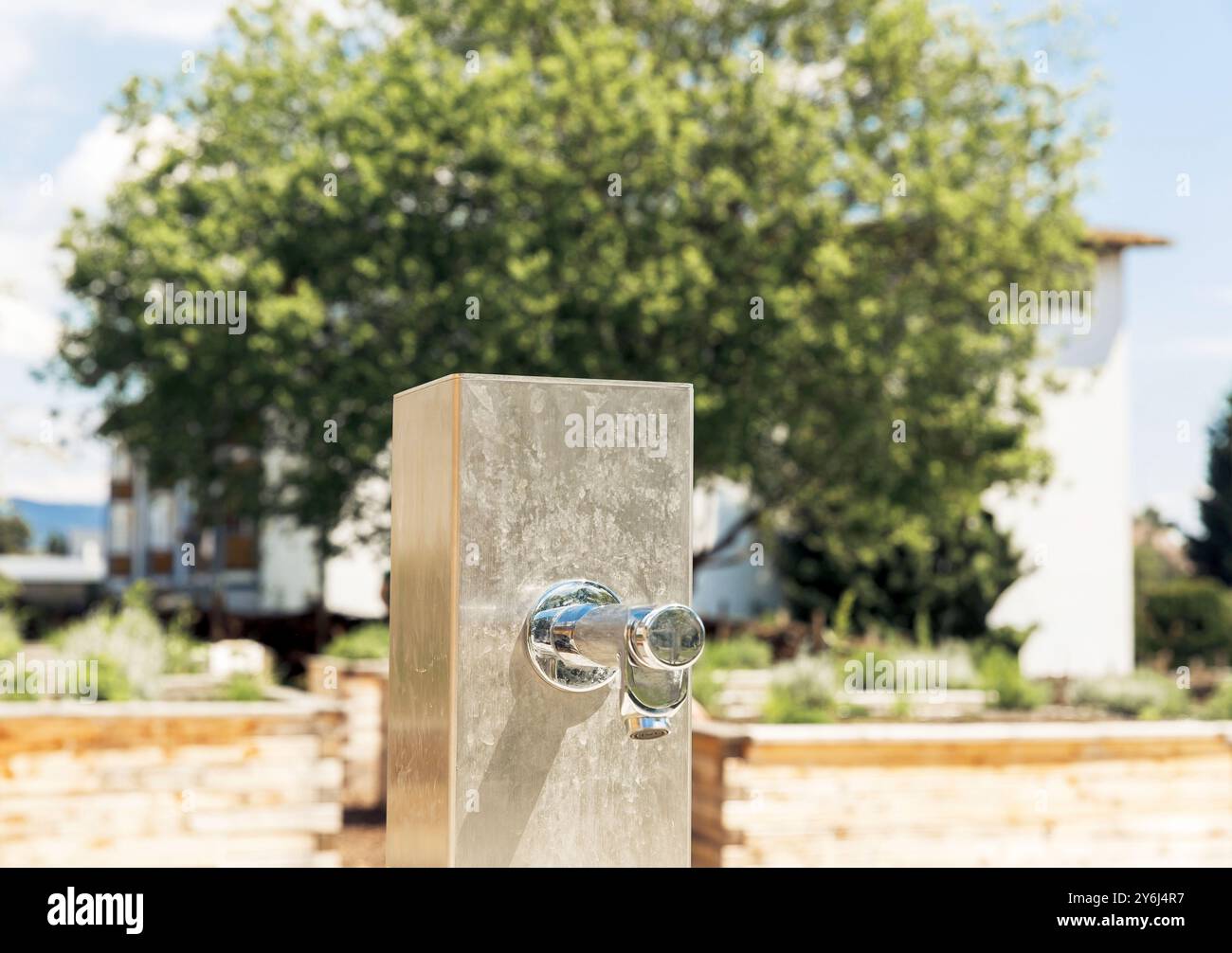 Robinet extérieur en acier inoxydable dans un jardin avec un fond flou, mettant en valeur le concept de réglage de la nature Banque D'Images