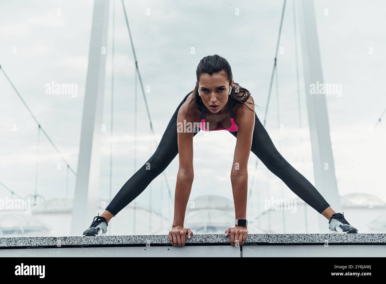 Dédié au fitness. Jeune femme moderne en vêtements de sport s'étirant tout en s'échauffant à l'extérieur Banque D'Images