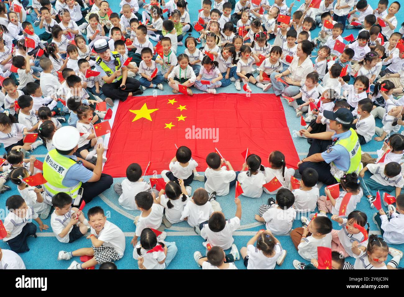 WUHU, CHINE - 26 SEPTEMBRE 2024 - des policiers et des enfants chantent l'hymne national pour célébrer la Journée nationale à Wuhu, province d'Anhui, Chine, sept Banque D'Images