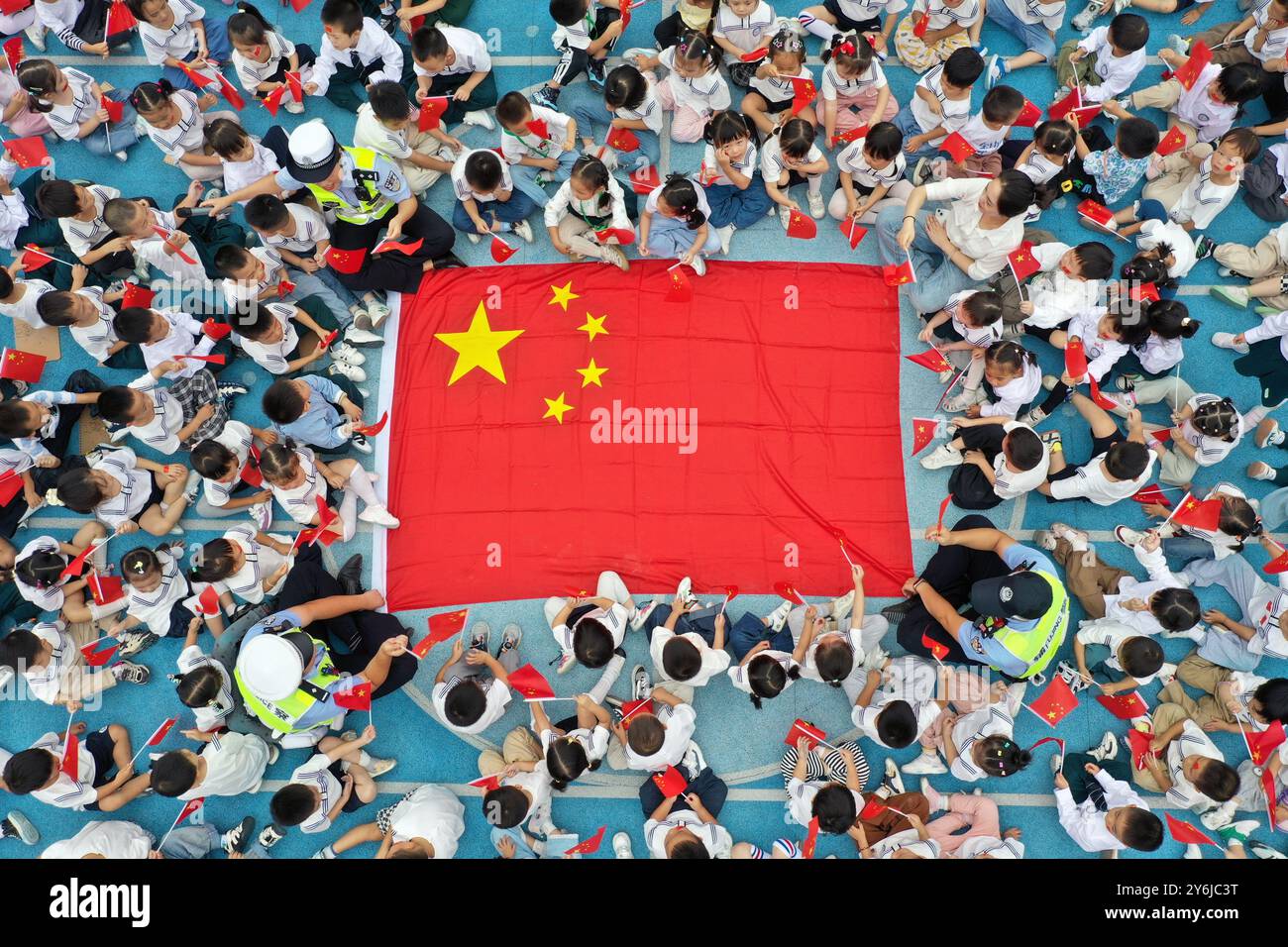 WUHU, CHINE - 26 SEPTEMBRE 2024 - des policiers et des enfants chantent l'hymne national pour célébrer la Journée nationale à Wuhu, province d'Anhui, Chine, sept Banque D'Images