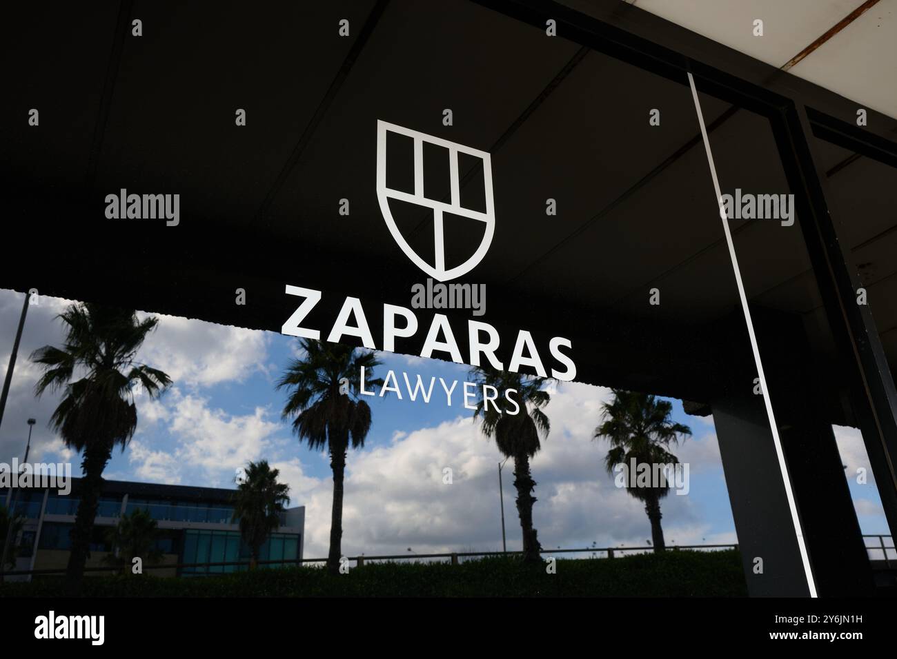 Logo de Zaparas Lawyers, avec emblème de bouclier, dans la fenêtre des bureaux d'Oakleigh du cabinet d'avocats des blessures corporelles, avec reflet de palmiers Banque D'Images