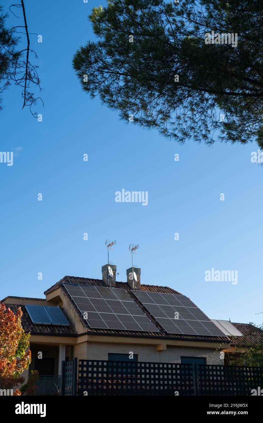 détail du toit d'une maison individuelle avec cheminées et panneaux solaires photovoltaïques pour une énergie alternative et durable sur le toit. C'est l'automne Banque D'Images