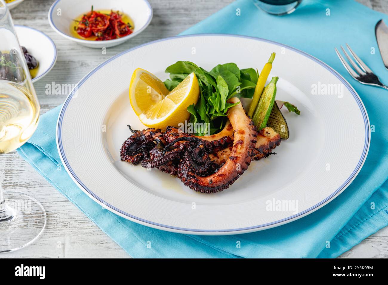 Poulpe grillé avec roquette et mini légumes sur une assiette en porcelaine blanche Banque D'Images
