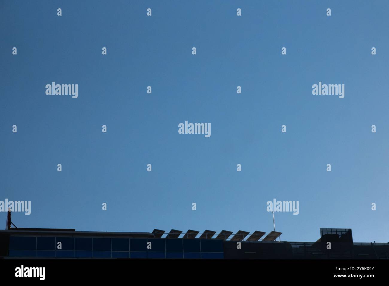 Vue rétroéclairée du toit d’un immeuble de bureaux moderne avec installation de panneaux solaires photovoltaïques sur le toit communautaire. Concept durable et ecolo Banque D'Images