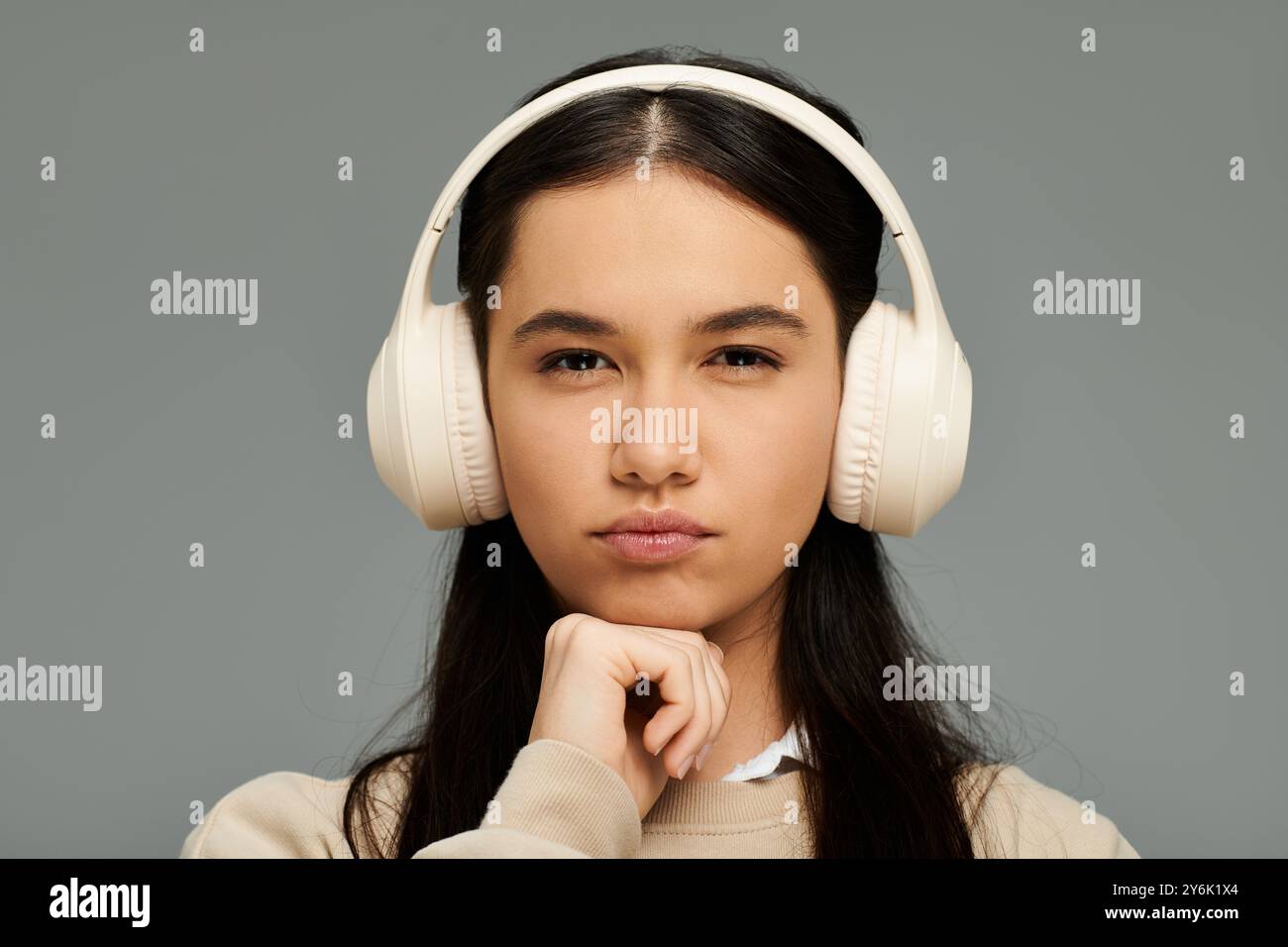 Élégamment habillée, elle réfléchit profondément, des écouteurs enveloppant ses pensées de rythme musical. Banque D'Images