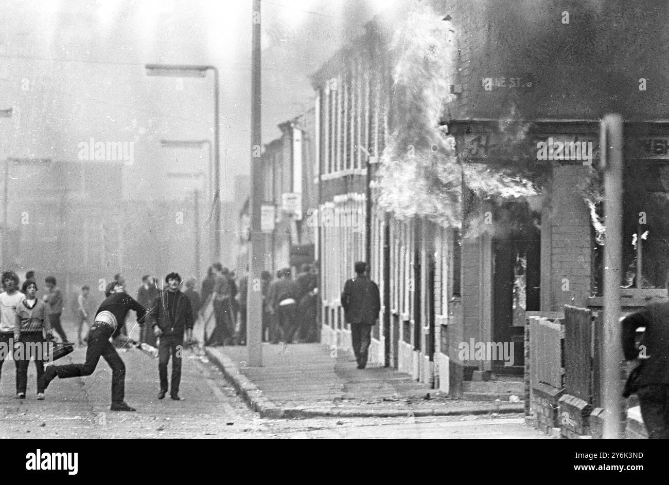 Belfast. Un jeune lance une bombe à essence dans un magasin de mode capillaire , l'allumant. C'était l'un des nombreux cas d'émeutes et de violence entre factions catholiques et protestantes dans la région. 16 août 1969 Banque D'Images