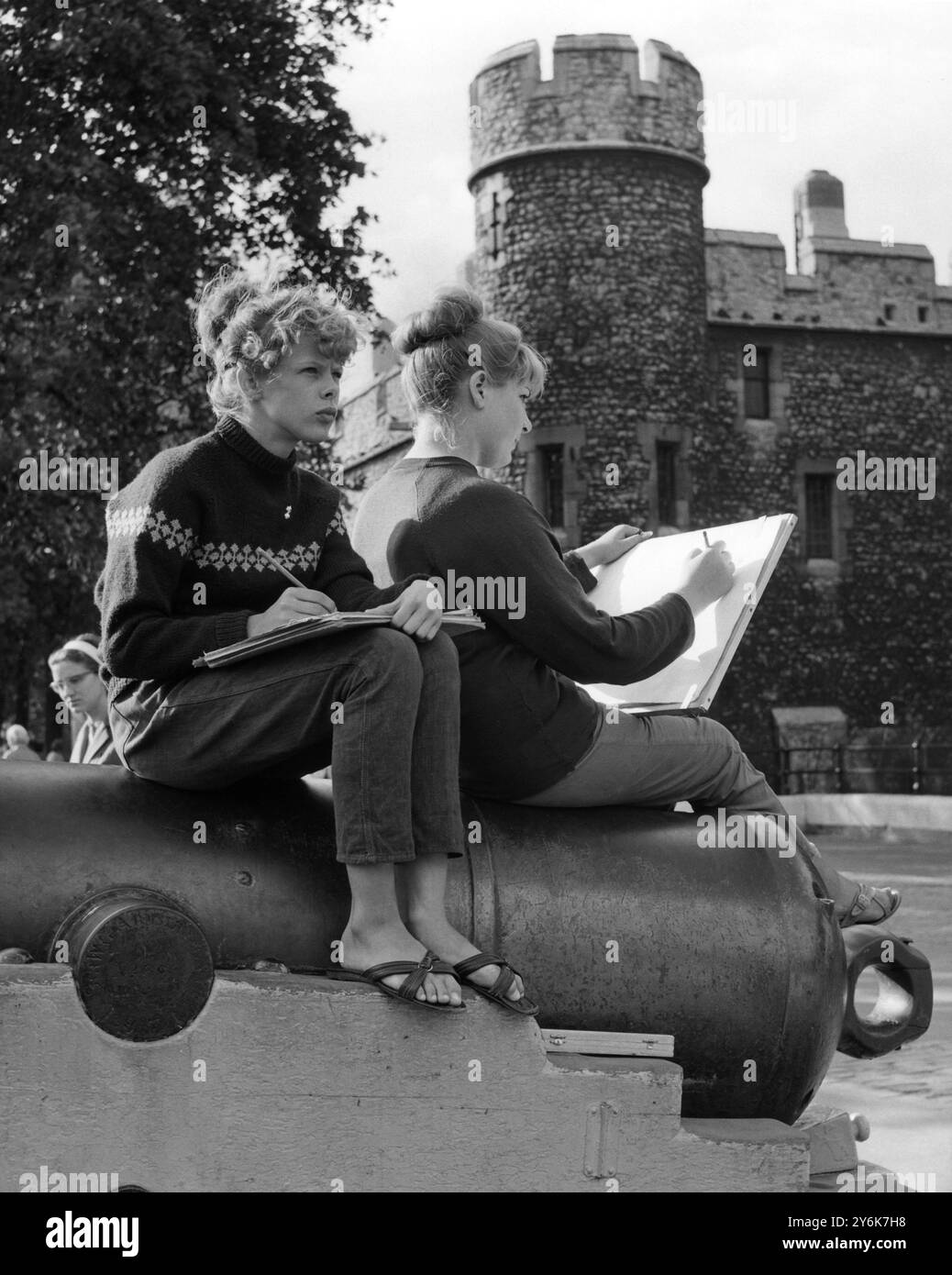 Barbara Cotton, étudiante en art, de Weston Street, Southwark, et Sally Linsley, écolière de 14 ans, d'Ethnard Road, Peckham, ont trouvé l'un des canons de la Tour de Londres un siège idéal pour une session de croquis en plein air. Les Girls ont passé une partie de leurs vacances d'été à esquisser des vues sur le londres historique. 1962 Banque D'Images