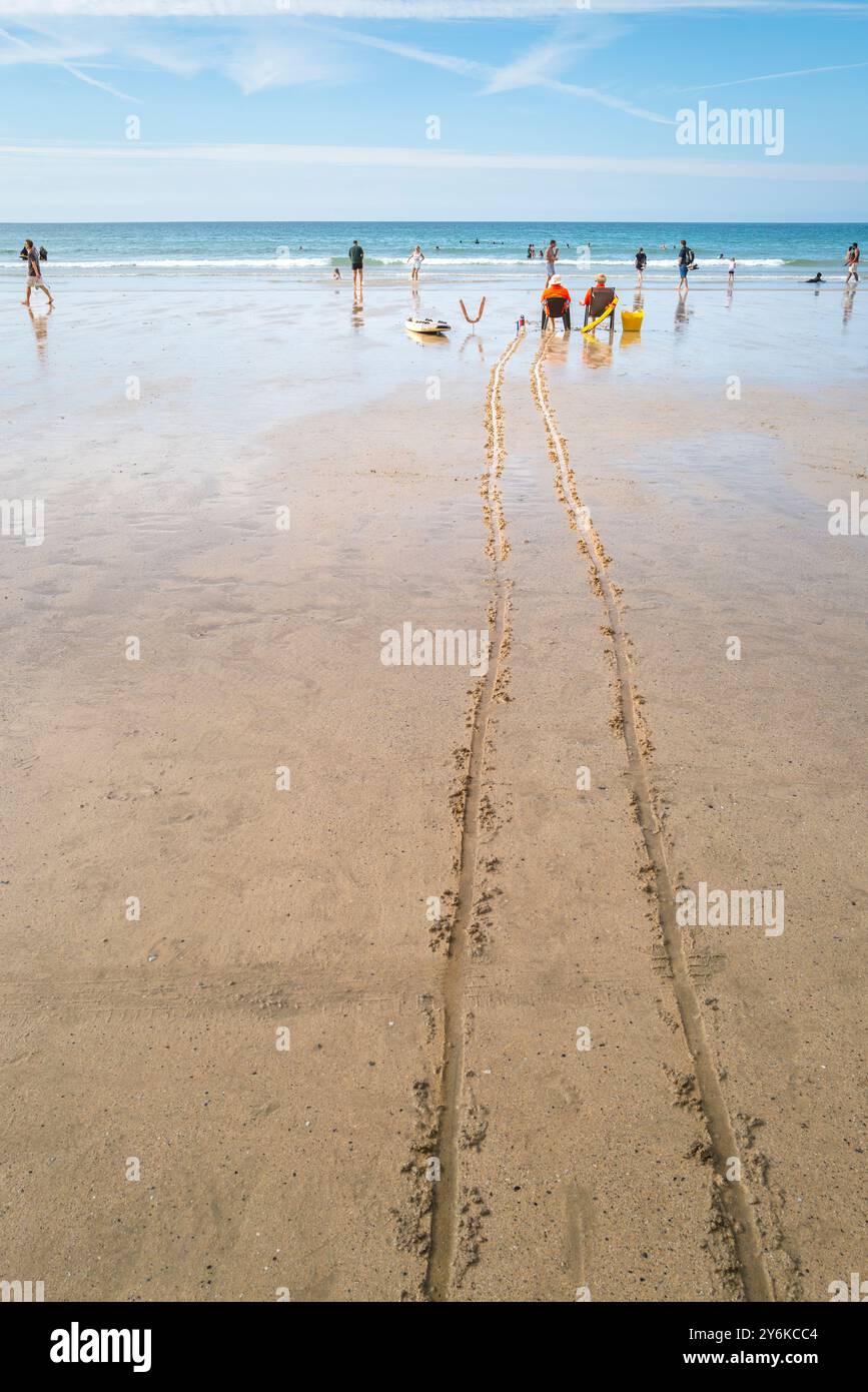 Deux sauveteurs RNLI assis dans des chaises en service regardant les vacanciers dans la mer à marée basse sur GT Great Western Beach à Newquay en Cornouailles au Royaume-Uni Banque D'Images