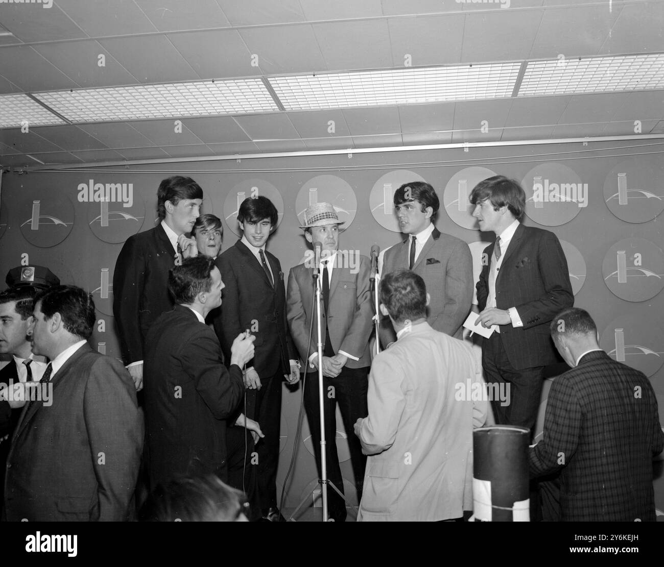 New York : le groupe musical anglais Dave Clark Five est interviewé à leur arrivée à l'aéroport Kennedy de New York, le 24 mai, pour commencer une tournée de concerts de 16 jours dans l'est des États-Unis. Environ 2 500 adolescents criant ont accueilli le groupe à l'aéroport. Clark (2e à partir de la droite porte un badge sur son œil gauche - un souvenir de la récente performance du groupe à Halsingborg, Suède. 26 mai 1964 Banque D'Images