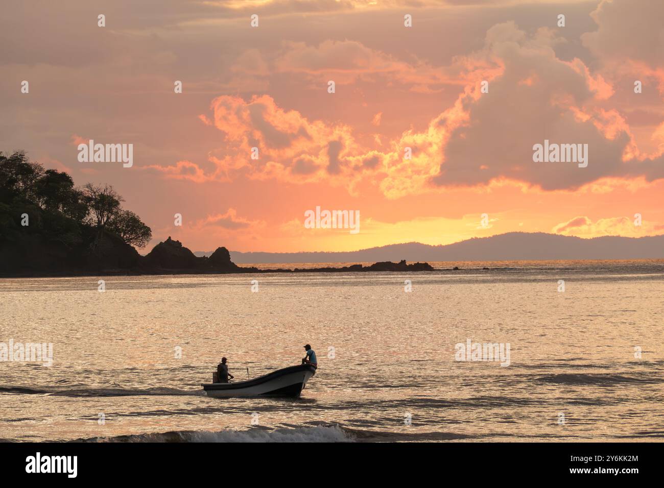 Coucher de soleil romantique dans des couleurs intenses à l'océan avec des nuages brillants à Santa Catalina, Panama avec silhouette de bateau pêcheur au premier plan Banque D'Images