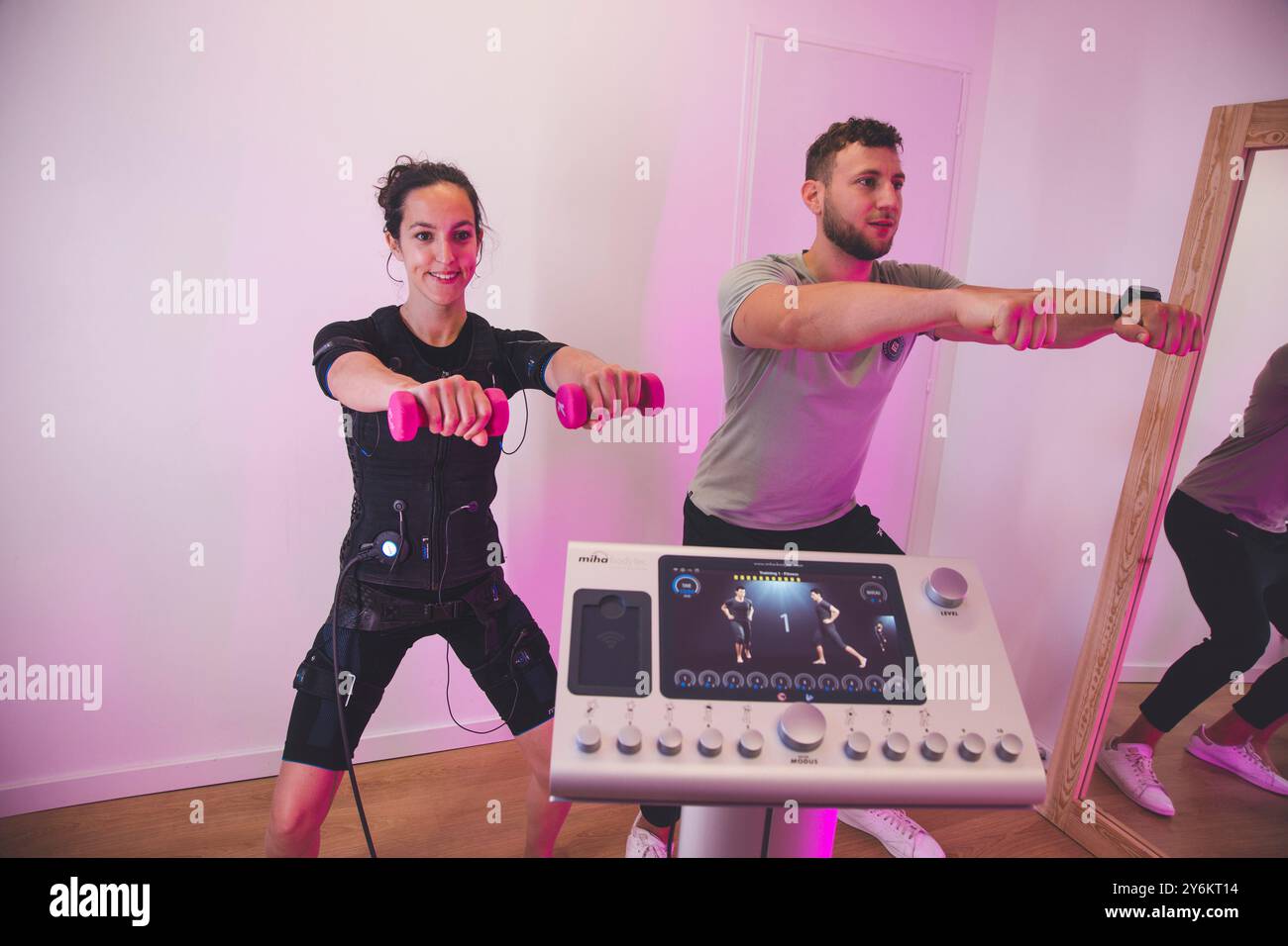 Femme aux cheveux foncés dans la trentaine faisant de l'électrostimulation EMS avec un entraîneur sportif Banque D'Images