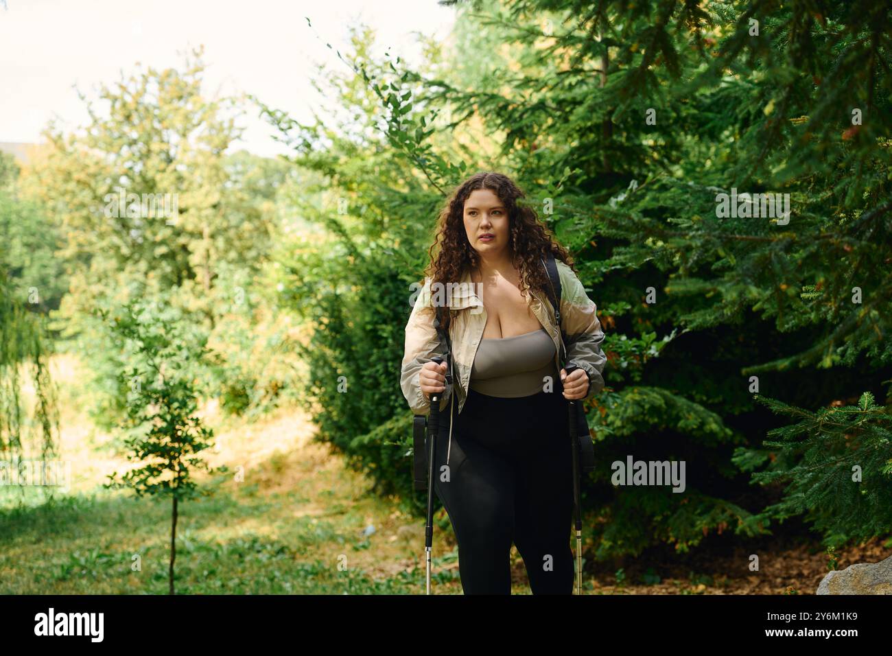 Une femme confiante profite d'une promenade paisible à travers une forêt verdoyante entourée par la nature. Banque D'Images