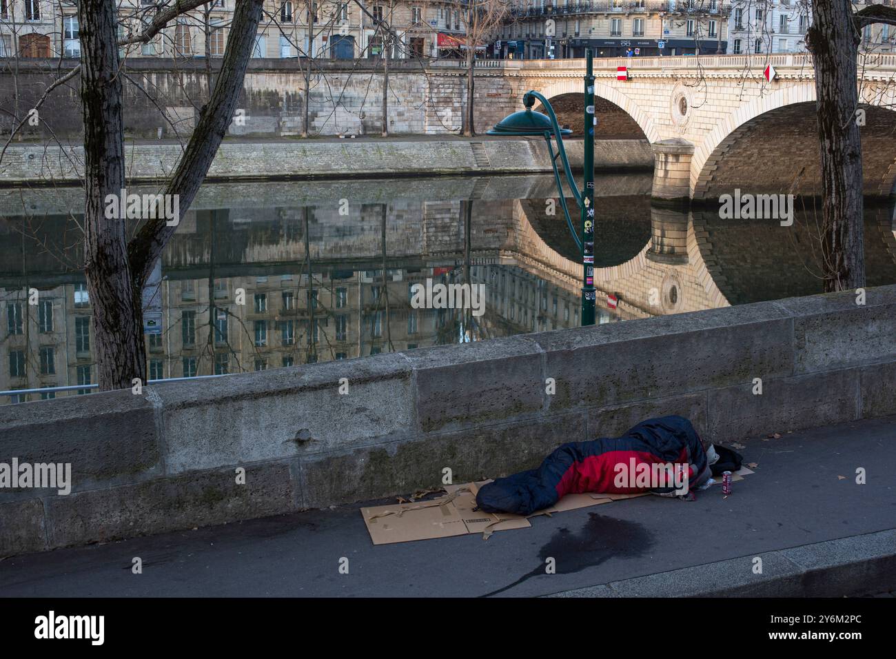 France, Paris, 75, 4ème arrondissement, Quai des Celestins, personne sans-abri allongée dans une couette sur une boîte en carton au sol, février 2023. Banque D'Images