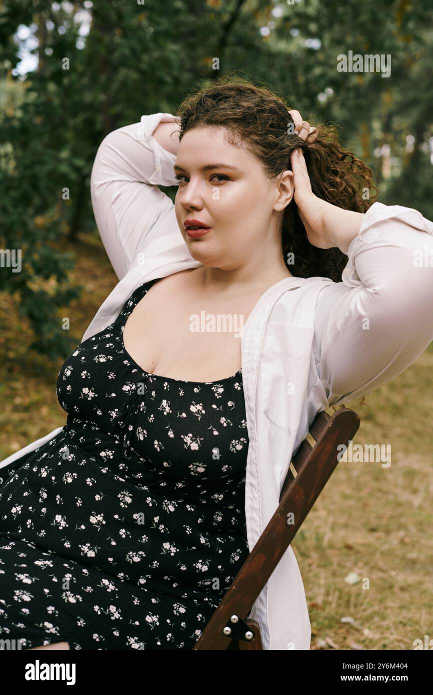 Une femme de taille plus confiante se détend dans un champ, embrassant sa beauté et sa nature. Banque D'Images