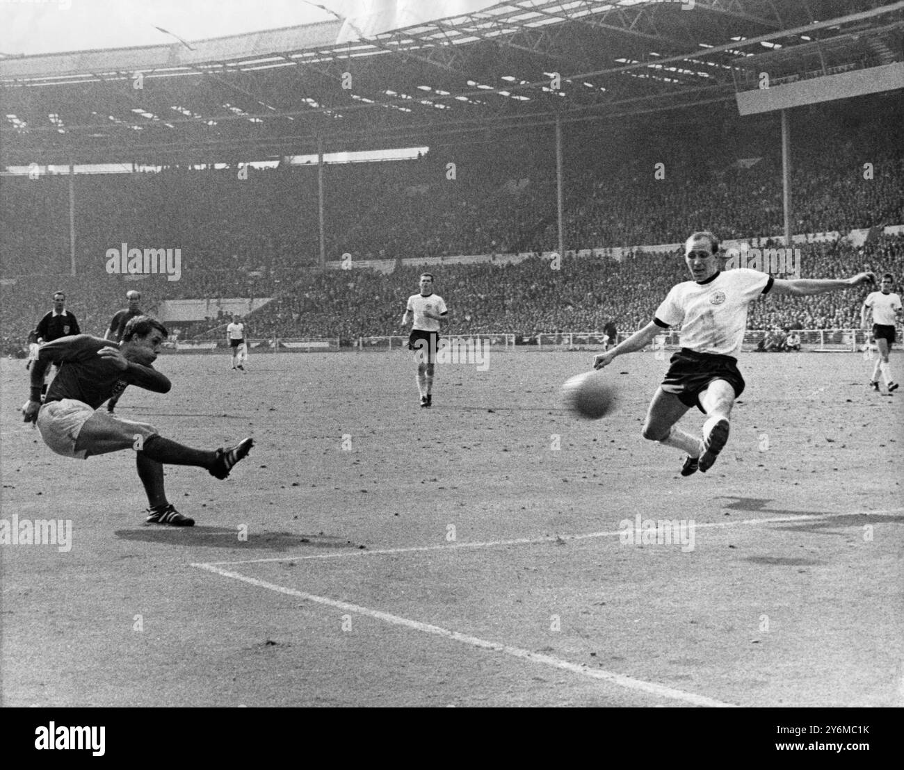 Hurst met l'Angleterre sur la voie de la victoire typiquement gonflant ses joues, Geoff Hurst bat le ballon devant Wili Schulz (Allemagne de l'Ouest) pour marquer le troisième but de l'Angleterre en temps supplémentaire de la finale de la Coupe du monde à Wembley. Au centre, Franz Beckenbauer Angleterre a gagné 4-2 Banque D'Images