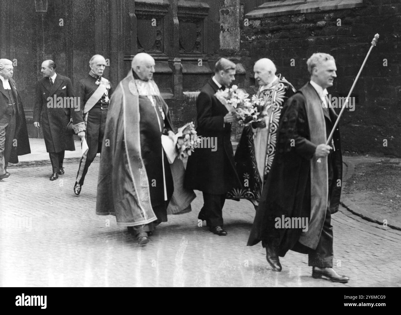 Le roi Édouard VIII fait la fête lors de la cérémonie de distribution de Maundy Money à l'abbaye de Westminster le jeudi Maundy. Le roi tenant des fleurs alors qu'il parlait à l'archevêque de Cantorbéry, Cosmo Lang, à hs dpearture après la cérémonie. Le port des fleurs remonte à la Grande peste. 1936 Banque D'Images