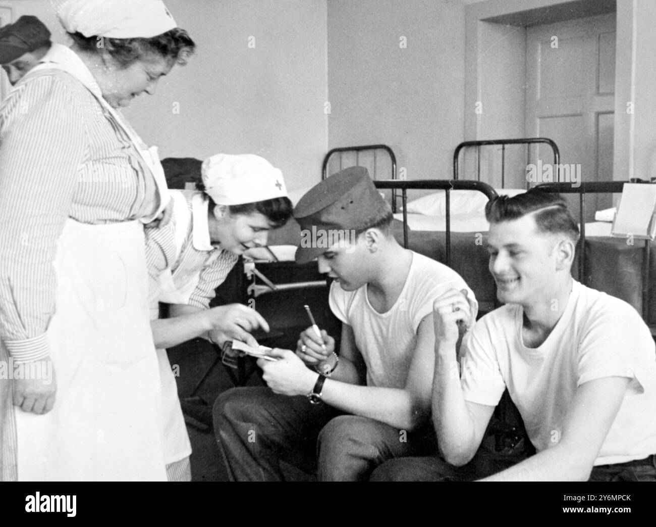 Friedberg, Allemagne : dans sa dernière performance, le chanteur de Rock 'n Roll, maintenant soldat Elvis Presley (à gauche) a donné du sang! Sa performance était purement volontaire cependant - lui et 179 autres hommes de la 3rd. Davison blindé , y compris le soldat George Mayers, de Battle Creek, Michigan, a fait don de sang à la Croix-Rouge allemande, au Ray Barracks ici, le 16 janvier. Après le don, Elvis signe des autographes pour les infirmières de la Croix-Rouge allemande le 18 janvier 1959 Banque D'Images