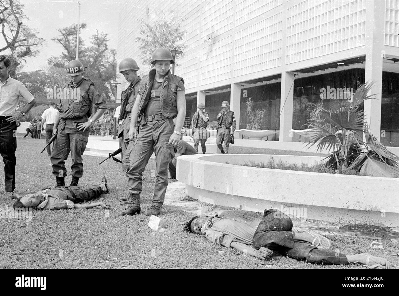 Siagon : police militaire américaine vue avec les corps de guérilleros Viet Cong tués quand ils ont essayé de prendre d'assaut l'ambassade des États-Unis ici le 31 janvier. Ils sont allongés dans le terrain de l'ambassade avec le bâtiment en arrière-plan. 3 février 1968 Banque D'Images