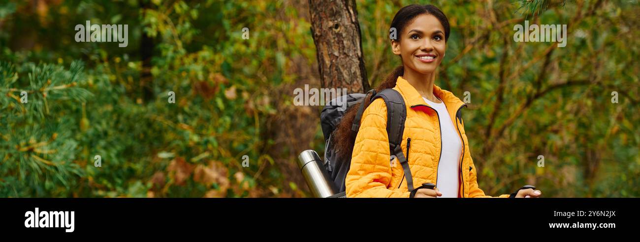 Une jeune femme joyeuse explore un sentier forestier, entouré par les riches couleurs du feuillage automnal. Banque D'Images