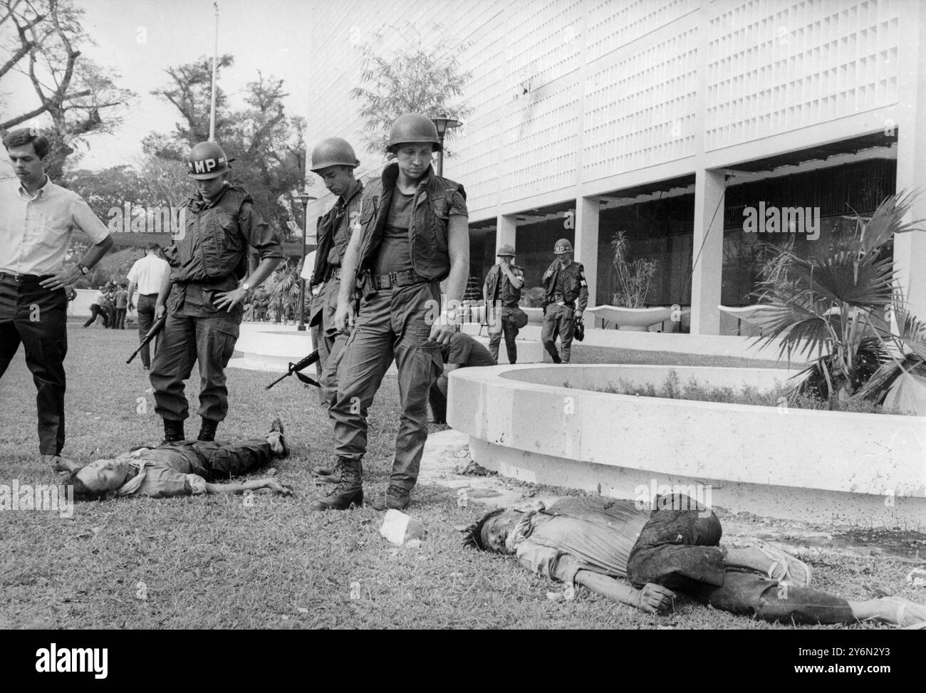 La police militaire américaine vue avec les corps de guérilleros Viet Cong tués après avoir tenté de prendre d'assaut l'ambassade américaine le 31 janvier 1968. Ils sont allongés sur le terrain de l'ambassade avec le bâtiment en arrière-plan. 3 février 1968 Banque D'Images