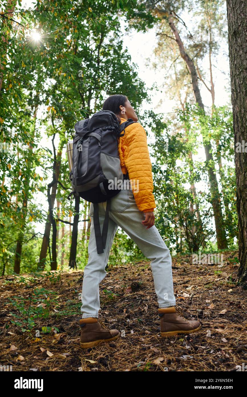 Dans une forêt automnale animée, une jeune femme explore la nature, incarnant un esprit aventureux et un mode de vie actif. Banque D'Images