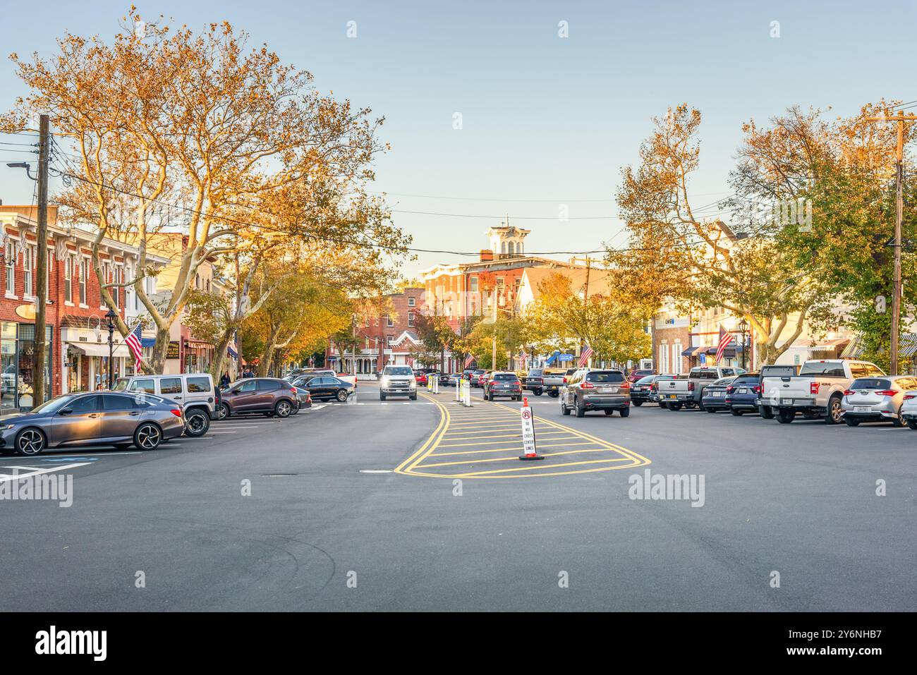 SAG Harbor, NY - 23 octobre 2023 : vue sur la rue principale bordée de bâtiments historiques en briques et d'arbres au coucher du soleil. Banque D'Images