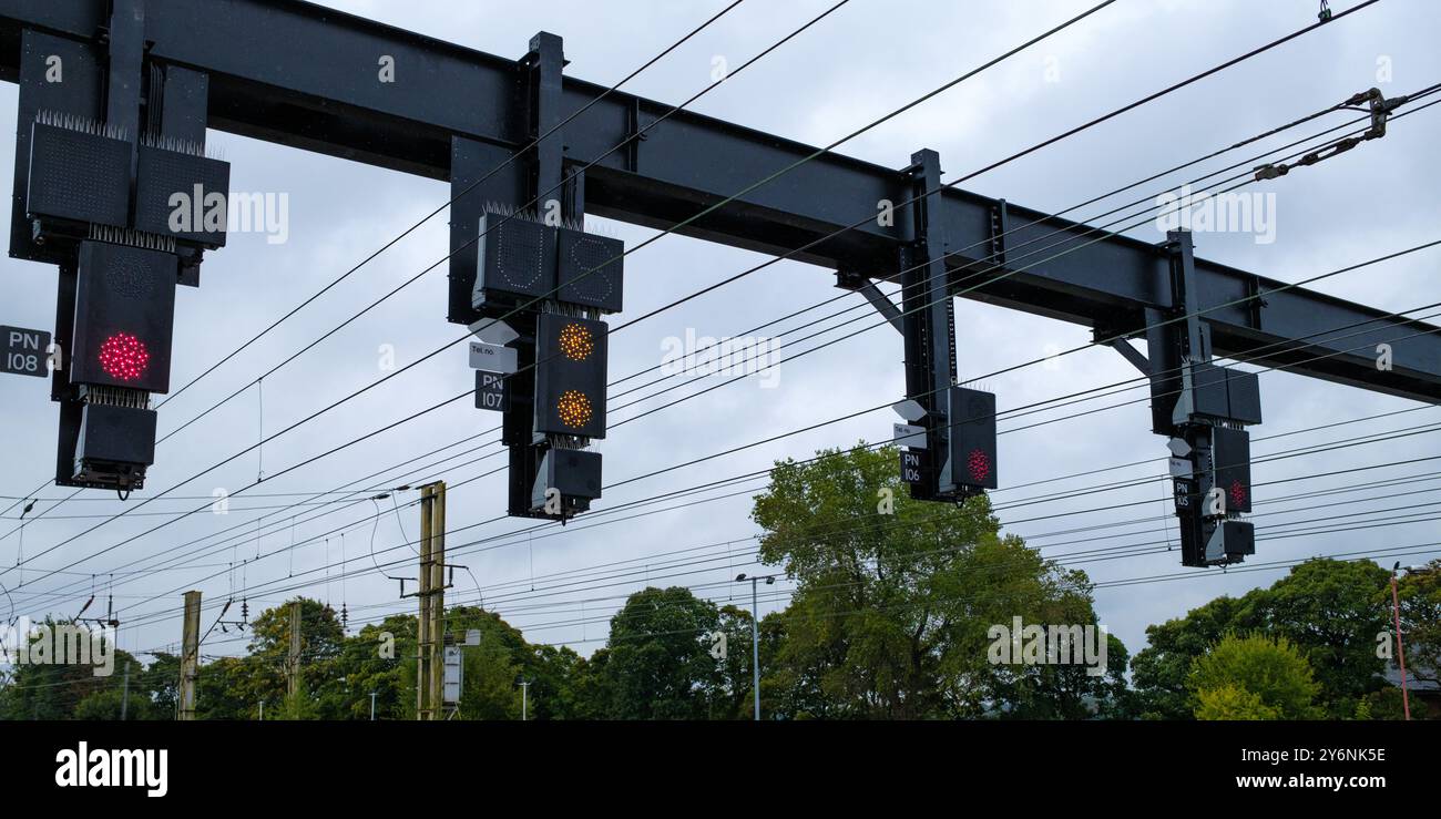 Signaux ferroviaires aériens contre un ciel nuageux, guidant les trains sur leur trajet. Banque D'Images