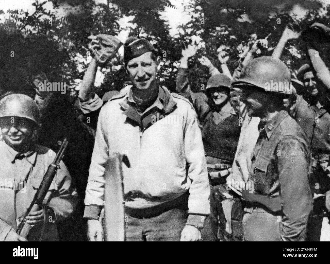 Le général Mark Clark, entouré de troupes britanniques et américaines acclamées de la Cinquième armée et de la force de tête de plage, est vu au lieu de rencontre à Borgo Grappa, un village entre les marais de Pontine et Anzio. Le général habituellement sombre regardant s'est détendu dans un large sourire. Juin 1944 Banque D'Images