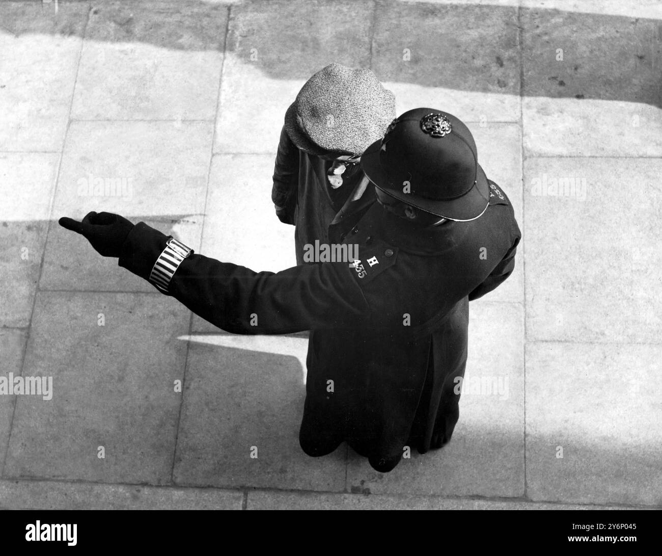 Homme en bonnet de tissu demandant probablement des instructions à un policier dans la rue Banque D'Images