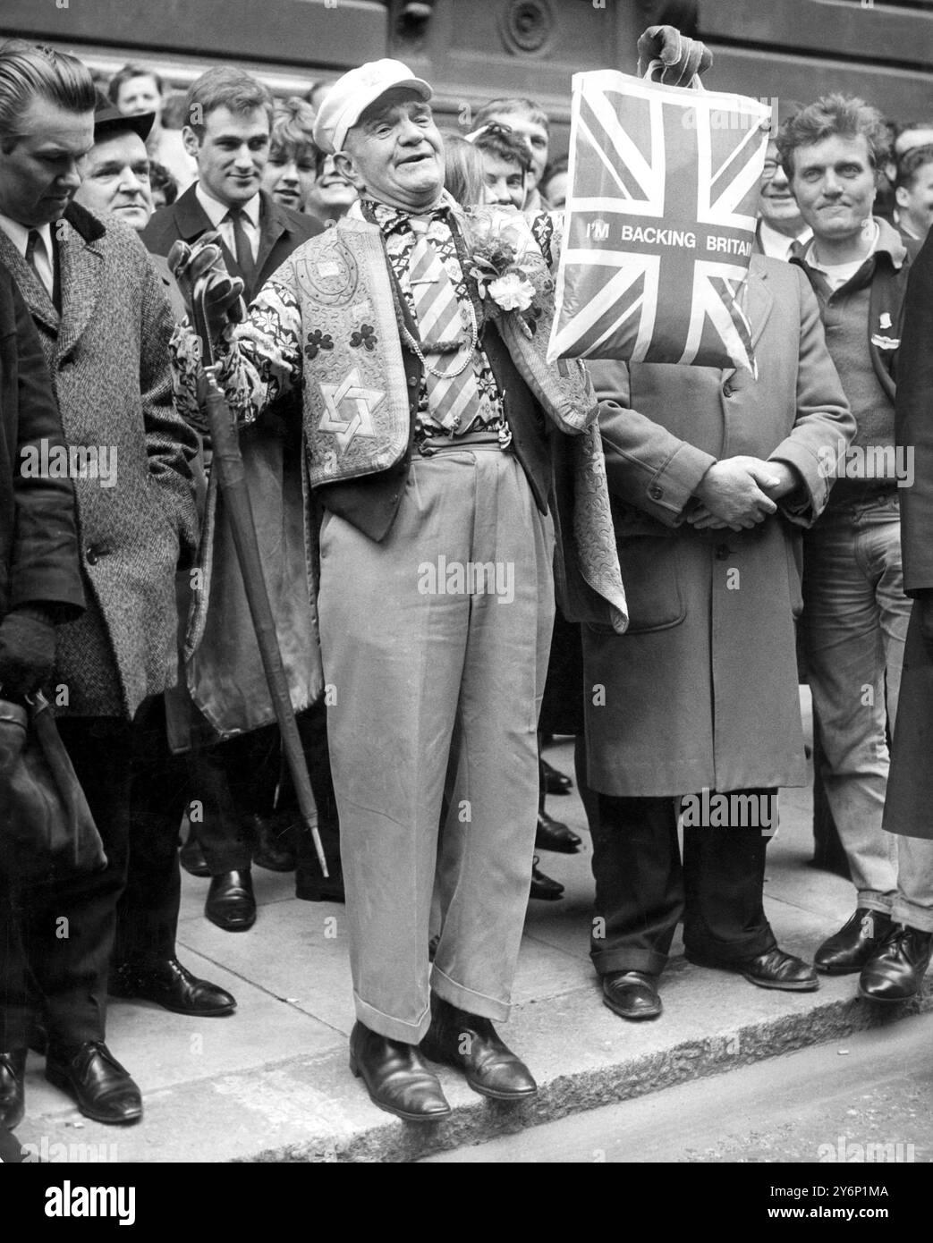 Budget Day dans Downing Street. Londres, et sommes-nous en bas - de cœur? Évidemment non, car ce Britannique non identifié et trop enthousiaste montre un sac de transport de l'Union Jack alors qu'il attend avec une foule de plusieurs centaines de personnes pour voir M. Roy Jenkins, le chancelier de l'Échiquier quitter le 11 Downing Street pour la Chambre des communes. Où il devait prononcer son discours sur le budget, cet après-midi (mardi). 19 mars 1968 Banque D'Images