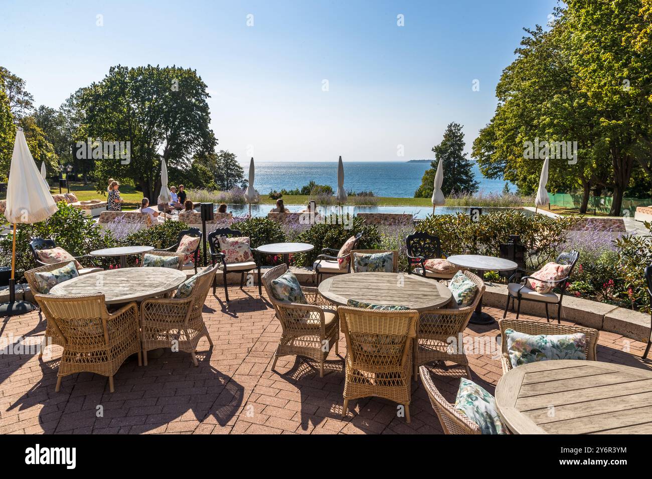 Des chaises en osier et des parasols bordent la terrasse du Maryhill Estate, surplombant l'Öresund. Les invités se détendent au bord de la piscine du domaine historique près de Landskrona. Skåne, Suède. Banque D'Images