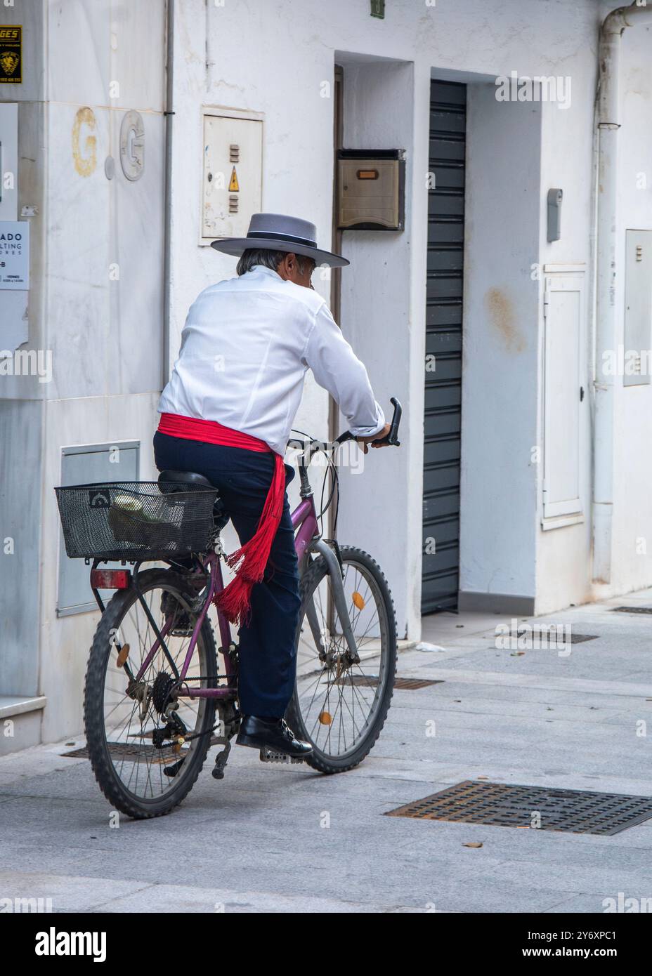 Un homme plus âgé vêtu d'un costume andalou typique, conduisant son vélo dans les rues de Fuengirola pendant la célébration de la Journée du cheval Banque D'Images