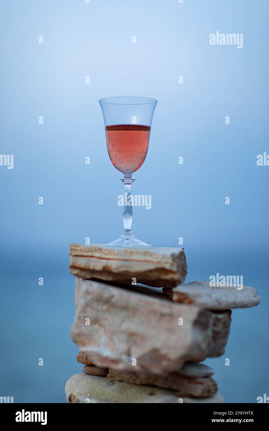 Verre de vin rose sur la pierre cairns sur fond de mer gros plan Banque D'Images