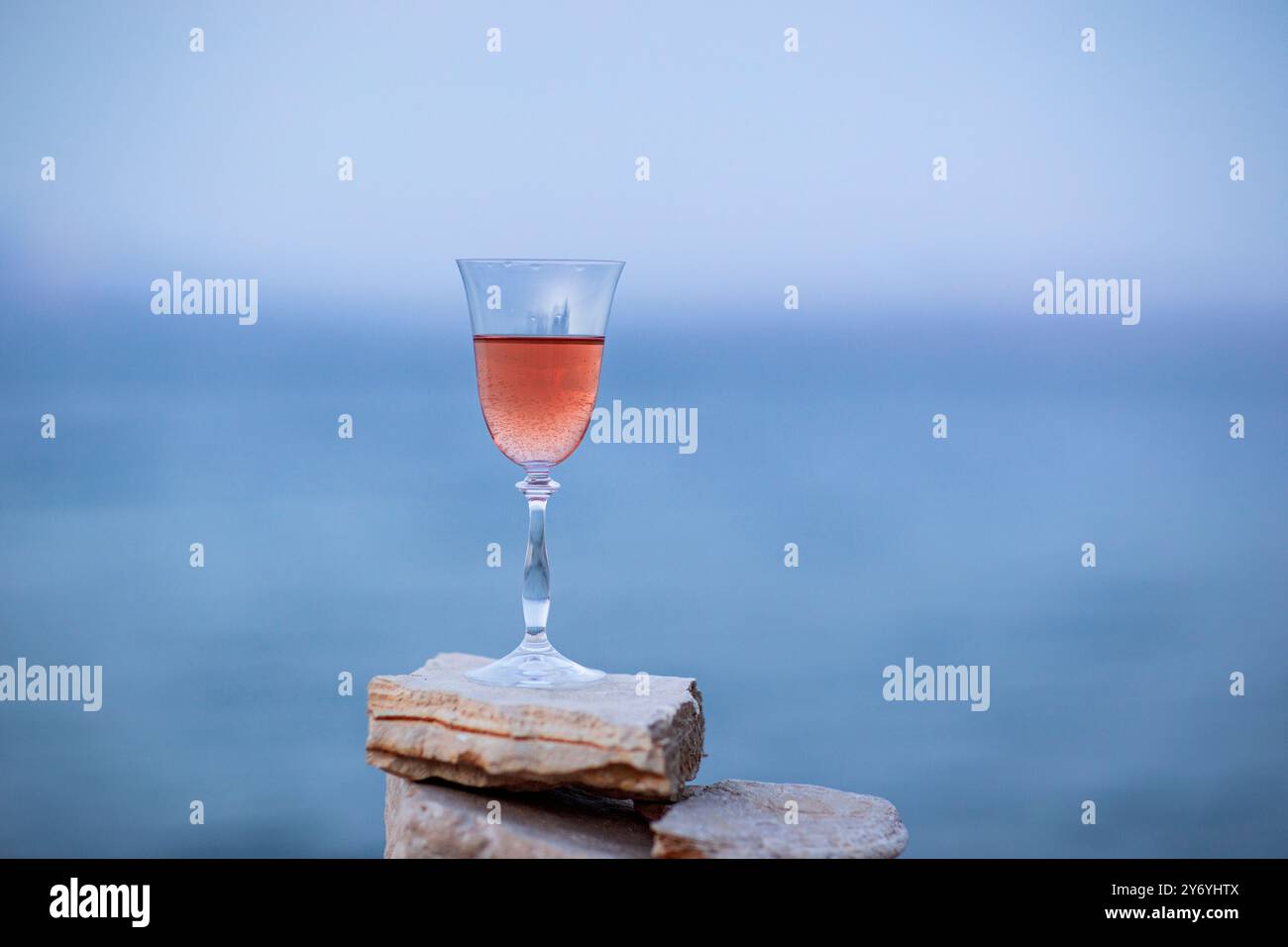 Verre de vin rose sur la pierre cairns sur fond de mer Banque D'Images