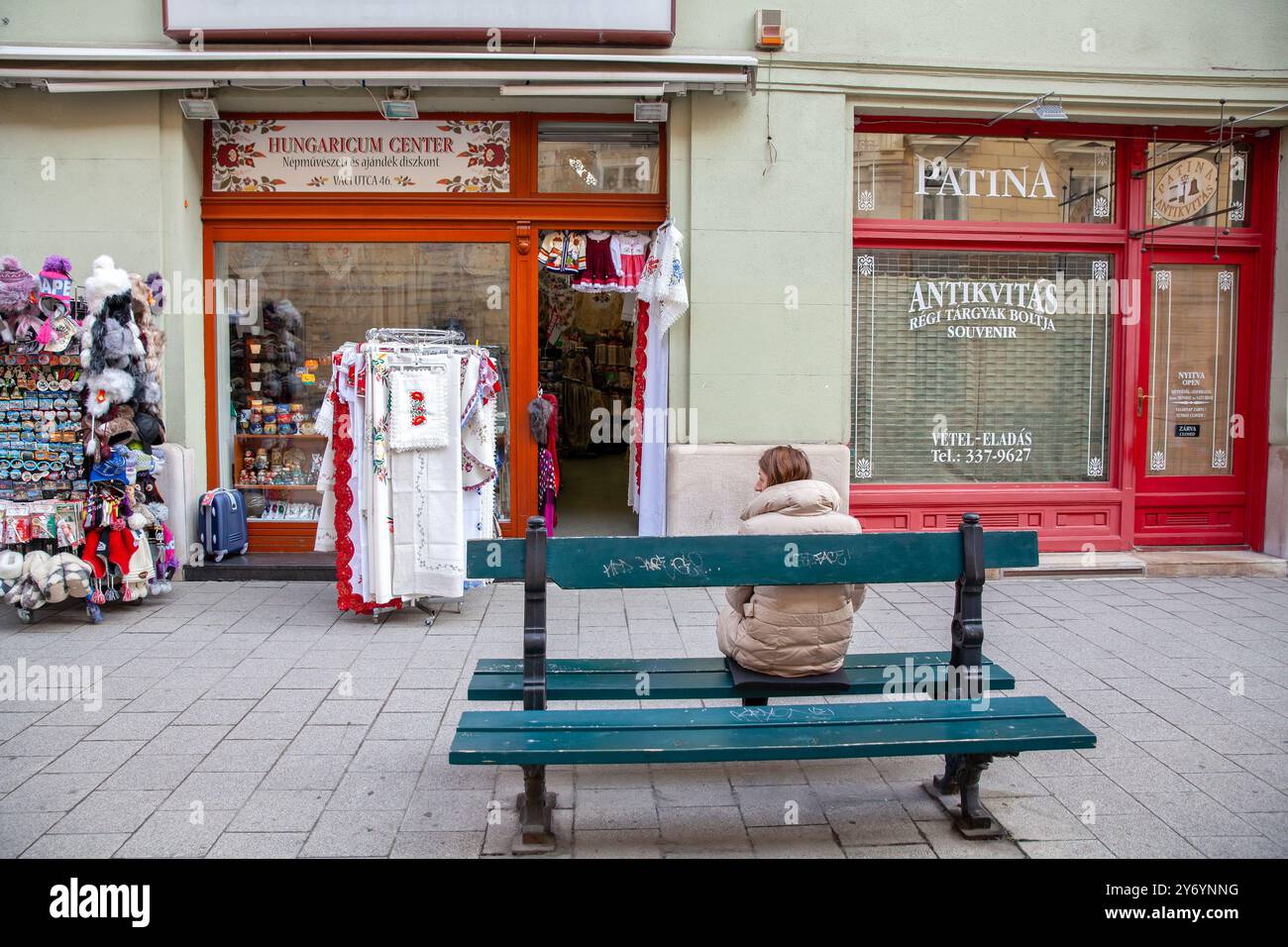 Femme Sat devant Une boutique de souvenirs hongroise sur la rue Vaci, Budapest Hongrie, Antikvitas souvenir Store Shop Front, temps d'automne Banque D'Images