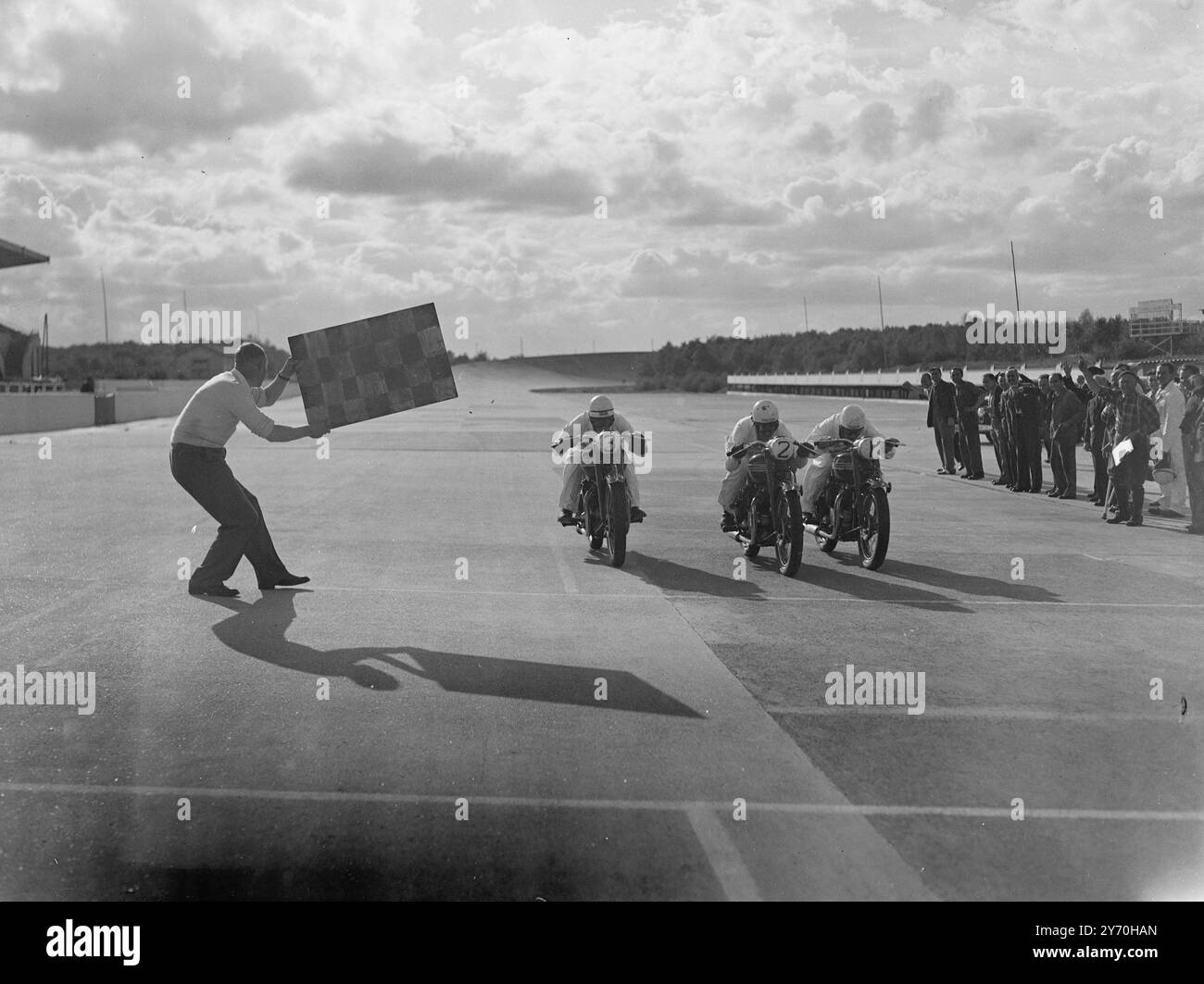 LE NOUVEAU ROYAUME-UNI à 100 MI/H - - le TRIOMPHE DE LA MOTO - - - - cinq motards sombres ont égayé les perspectives du dollar britannique quand ils se sont arrachés autour d'un parcours de 500 miles à des vitesses moyennes de plus de 90 miles à l'heure sur l'aérodrome de montlhery , près de Paris , France . - - Entre eux, les cinq hommes ont prouvé le courage de trois nouvelles Triumph ' Thunderbird ' machines verticales bicylindre 650 c.c. - un modèle 1950 conçu avec le marché américain en vue. - - A la fin des 500 miles chaque machine a fait un dernier tour à plus de 100 miles à l'heure . - - Les motos - première production ' Thunderbi Banque D'Images