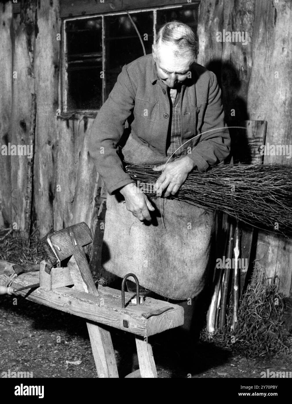 Artisan à Besom balais - - bois pour poignées est acheté chez les marchands locaux , ou d'un domaine . Il doit tomber et se préparer dans chaque cas. Le bouleau ou bruyère (et balai) qu'il obtient de la Commission des forêts. Sur cette image, M. Andrews est vu câbler un faisceau de bouleau - - 21 janvier 1957 Banque D'Images