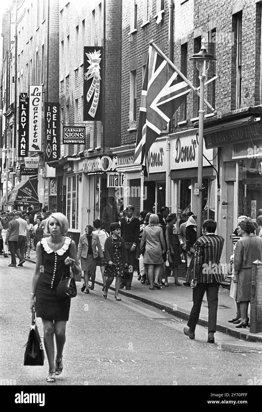 Le centre de la mode londonien pour les plus jeunes est Carnaby Street, la rue la plus connue, sinon la plus populaire de Londres. Les jeunes aux cheveux longs parlent loin les heures à Carnaby Street la Mecque des modes mod de la capitale anglaise tout au long de la mini-jupes aux derniers styles en vestes et pantalons pour hommes peut être acheté à Carnaby Street, la mode des jeunes HQ20 juillet 1967 Banque D'Images