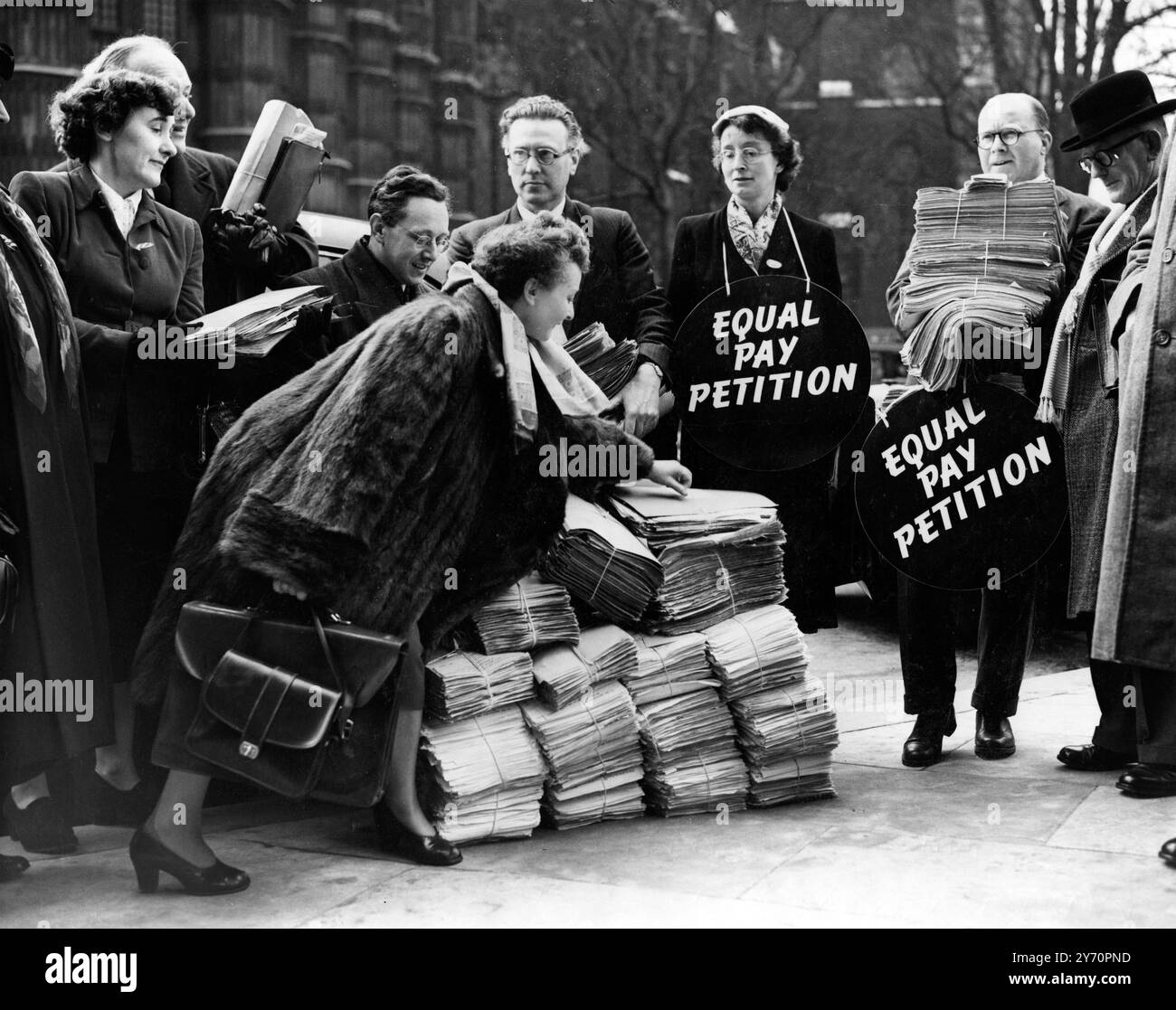 La pétition de la fonction publique sur l'égalité des salaires arrive à la Chambre Tied in massive bundles , une pétition en faveur de l'égalité des salaires pour les femmes organisée par les principales organisations du personnel de la fonction publique arrive à l'entrée Saint-Étienne de la Chambre des communes . Il sera présenté au Parlement par M. T C Pannell , député travailliste de Leeds, Ouest . Quelques minutes plus tôt, une pétition similaire organisée par le Comité de campagne pour l'égalité salariale était arrivée au Parlement par Mlle Irene Ward , députée conservatrice de Tynemouth . 8 mars 1954 Banque D'Images