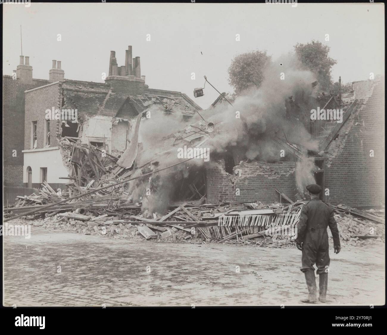 ABATTRE LES MURS DANGEREUX APRÈS UN GROS RAID. Bien que les maisons et les locaux commerciaux aient subi certains dommages, peu d’objectifs militaires auraient été touchés par le raid aérien le plus lourd de Londres. Le raid a continué toute la nuit, l'alarme ayant duré environ huit heures. Les abris anti-aériens ont réduit le nombre de victimes au minimum. LA PHOTO MONTRE:- un A.R.P, escouade de démolition tirant vers le bas des murs dangereux dans la région de Londres. 8 septembre 1940 CENSEUR NO : 66986 Banque D'Images